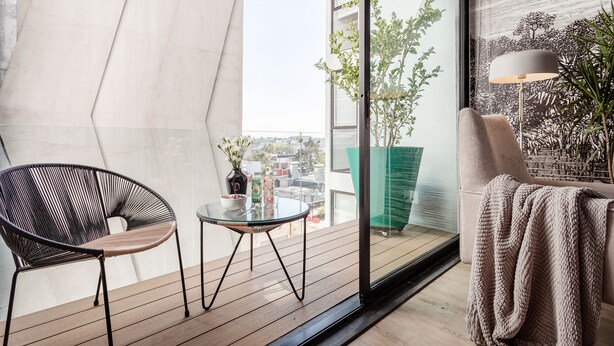 A modern balcony with a black chair, a small table, and a potted plant. - Illumé Urban Living - Apartments in the heart of Roma Norte (Mexico City)