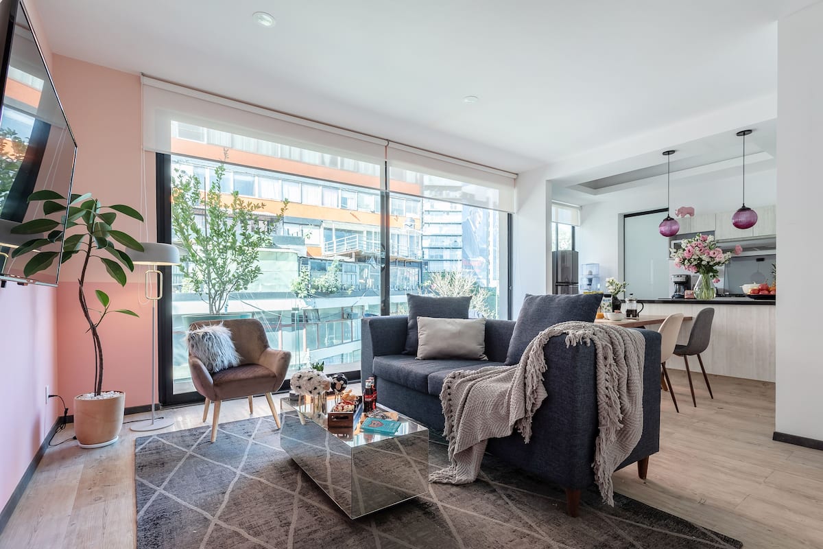 Ein modernes Wohnzimmer mit Sofa, Couchtisch und einem großen Fenster mit Blick auf Gebäude.