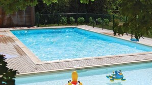 A rectangular swimming pool with a wooden deck surrounding it, enclosed by a metal fence. - Accès Piscine, Fitness, Sauna ! Maisonnette Climatisée avec Terrasse (Gramat)