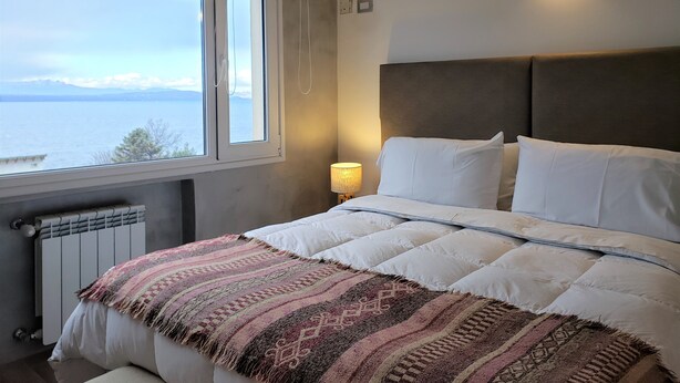 Una camera da letto con un letto, una finestra vista mare, una lampada a parete e un termosifone.