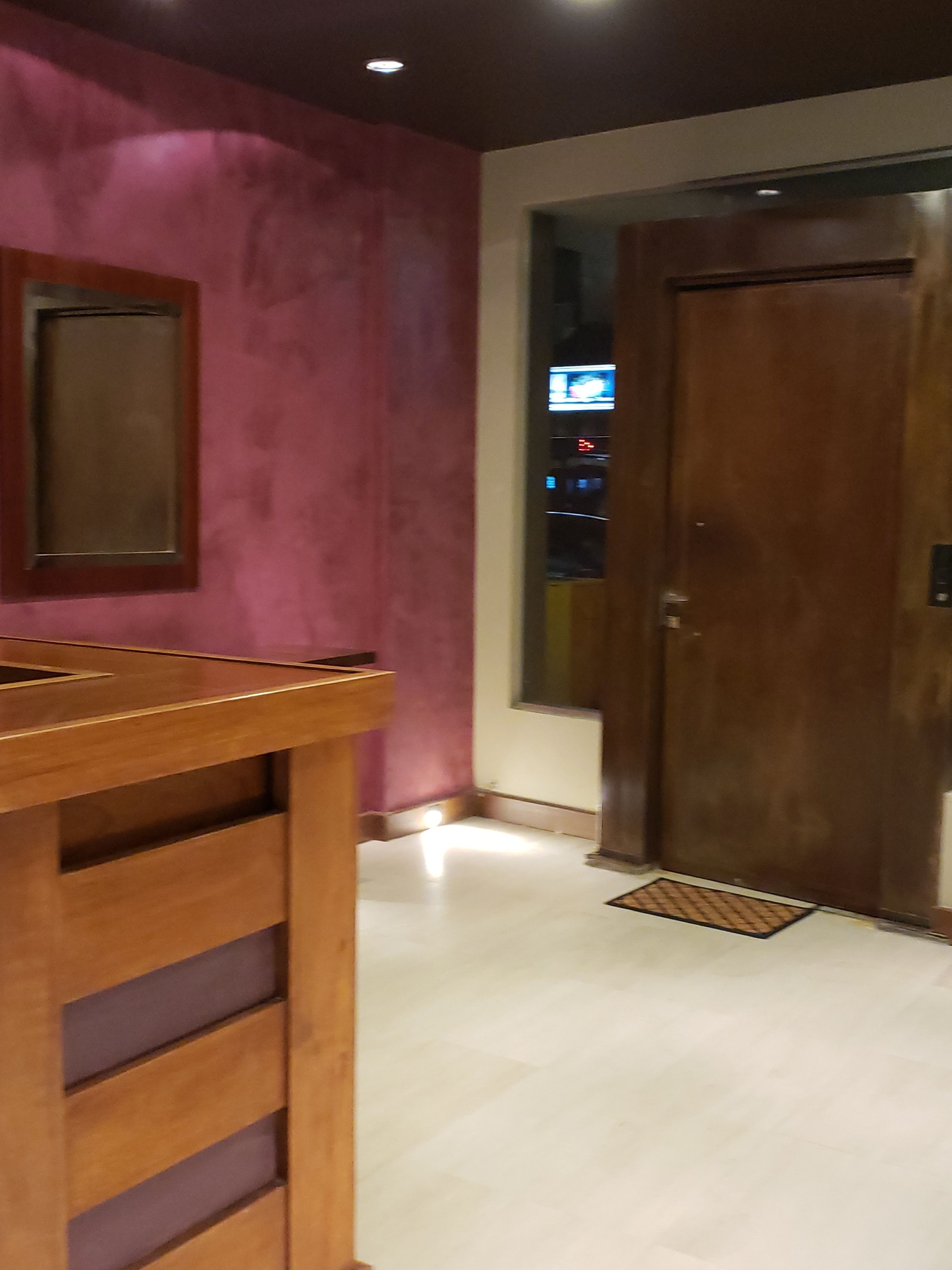 Une pièce avec une table en bois, une porte et un mur orné d’un panneau en retrait.