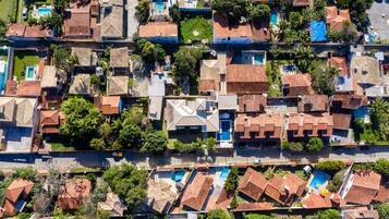 Vue aérienne d’un quartier résidentiel avec des maisons, des piscines et des espaces verts.