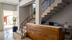 Ein moderner Empfangstresen mit Holzoptik, eine Treppe mit Metallgeländern und ein Topfpflanze.