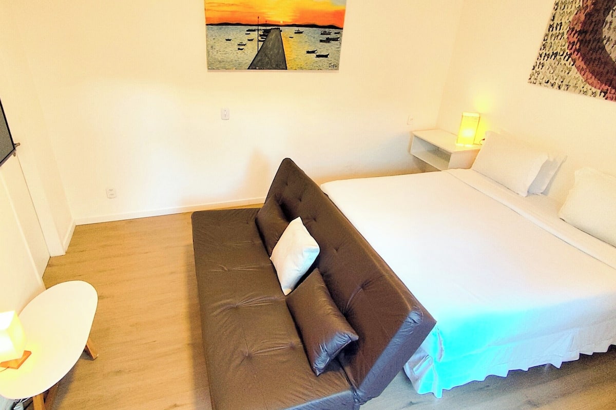 Un dormitorio con cama, sofá, escritorio y silla.