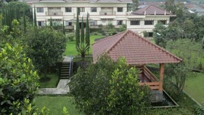 A large, multi-story building with a flat roof and a well-maintained garden in front. - Tangko Inn Resort (Cipanas)