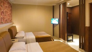 A hotel room with two beds, a television, and a wooden wardrobe. - Tangko Inn Resort (Cipanas)