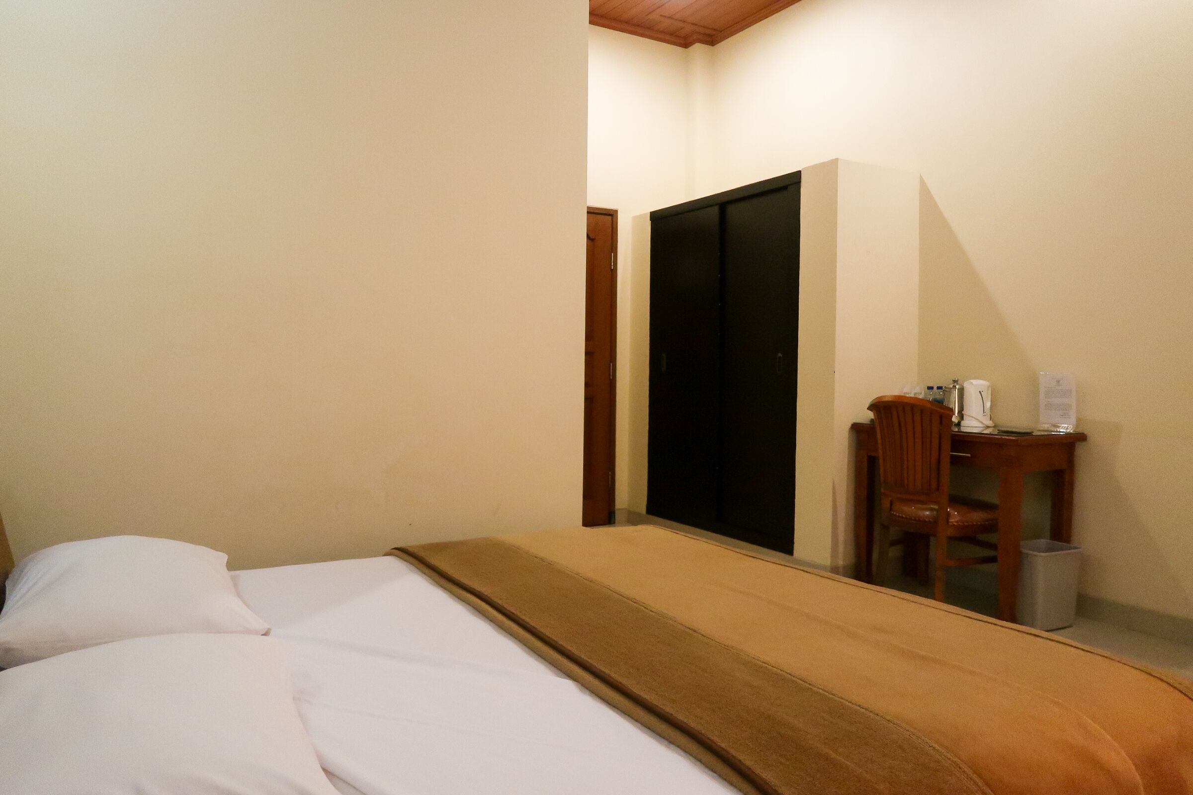 A bedroom with a bed, a desk, and a wardrobe.