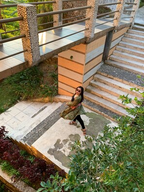 A staircase with a stone railing and a person walking down. - Tangko Inn Resort (Cipanas)