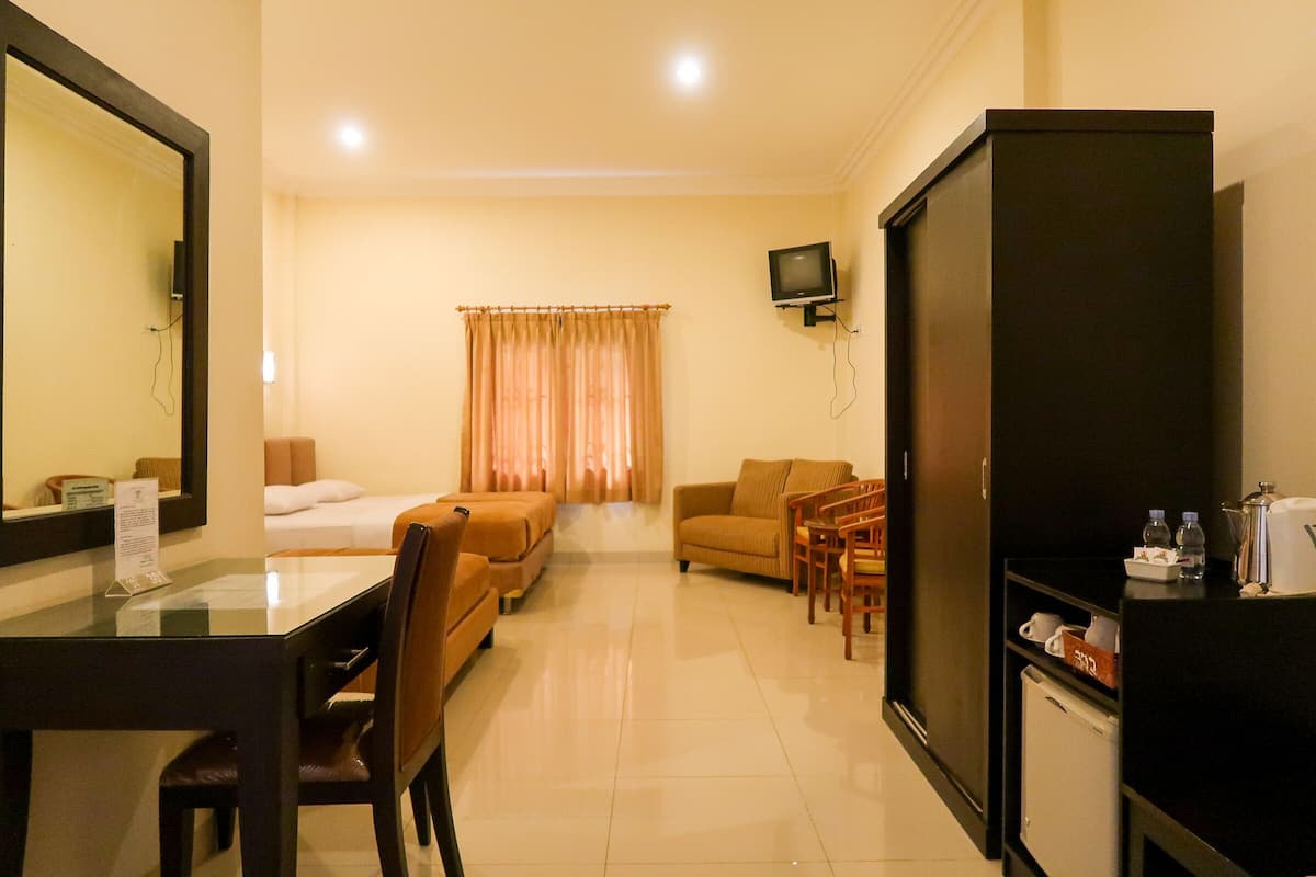 A hotel room with a bed, a sofa, a TV, a desk, and a cabinet.