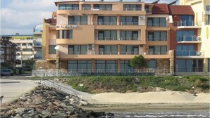 A multi-story hotel with balconies, located near a rocky shoreline. - Hotel Blian (Ravda)