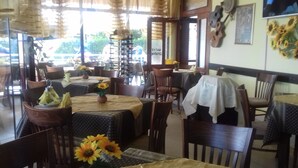 A restaurant with multiple tables and chairs, some with sunflowers on the tables. - Hotel Blian (Ravda)