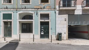 A building with numbered doors, a visible trash bin, and a gated entrance.