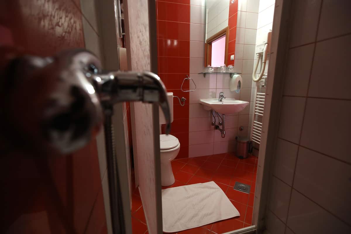 A bathroom with a red tiled floor, a white sink, and a toilet.