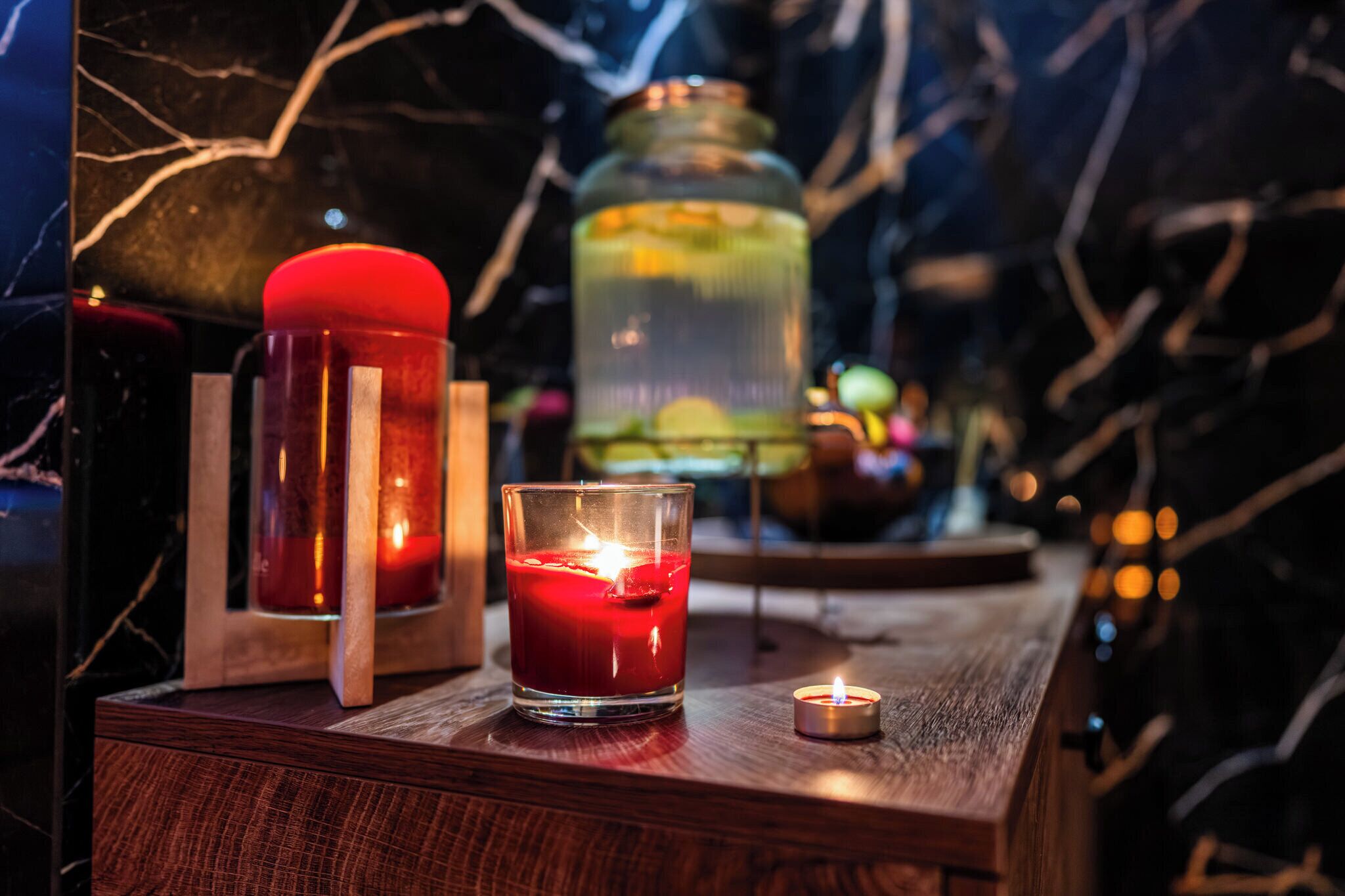 Una mesa de madera con una vela roja, un candelabro de cristal y una vela pequeña.