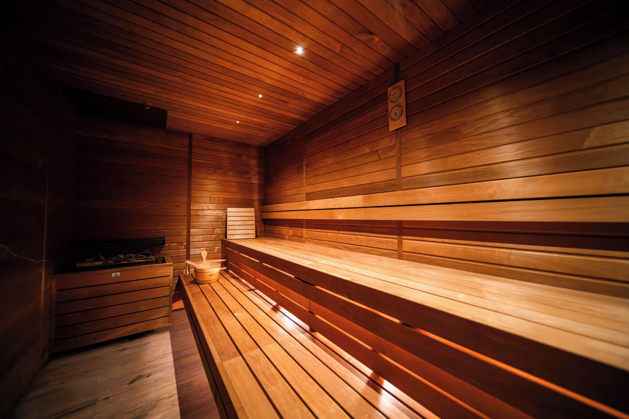 A sauna with wooden benches and a bench heater.