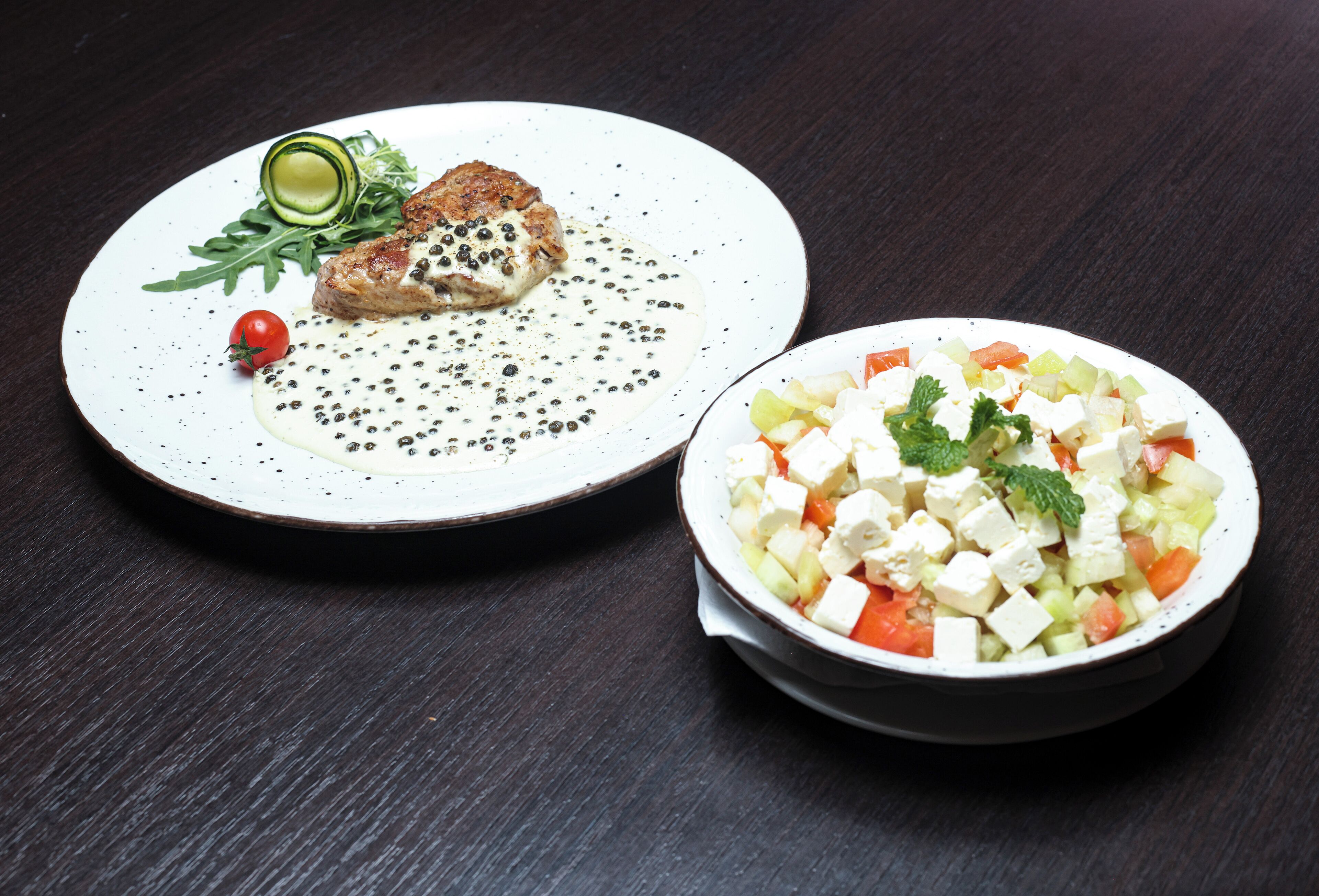 A plate with grilled chicken and a bowl of salad.