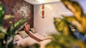 Quarto moderno com parede em padrão hexagonal, cama com cabeceira e luminária fixada na parede.