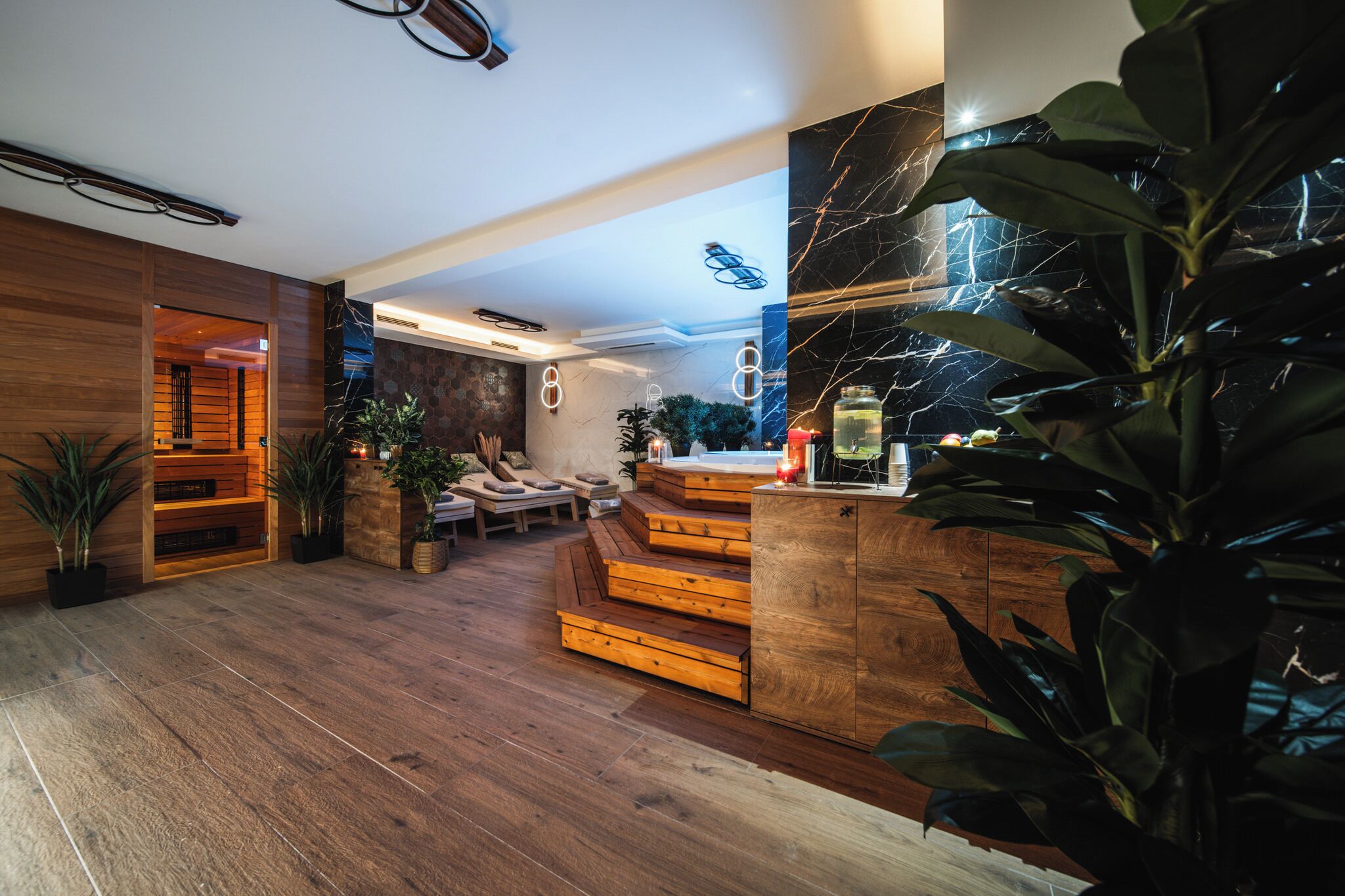 Un interior moderno con suelo de madera, una escalera y una zona de estar con cojines.