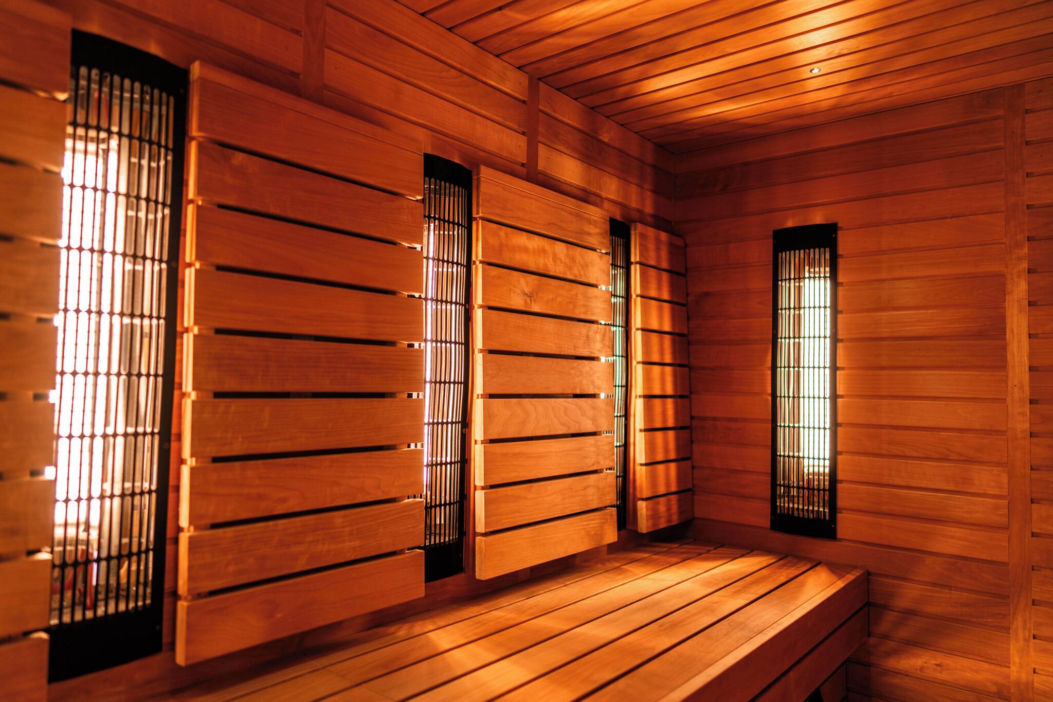 A wooden sauna with benches and vertical windows.