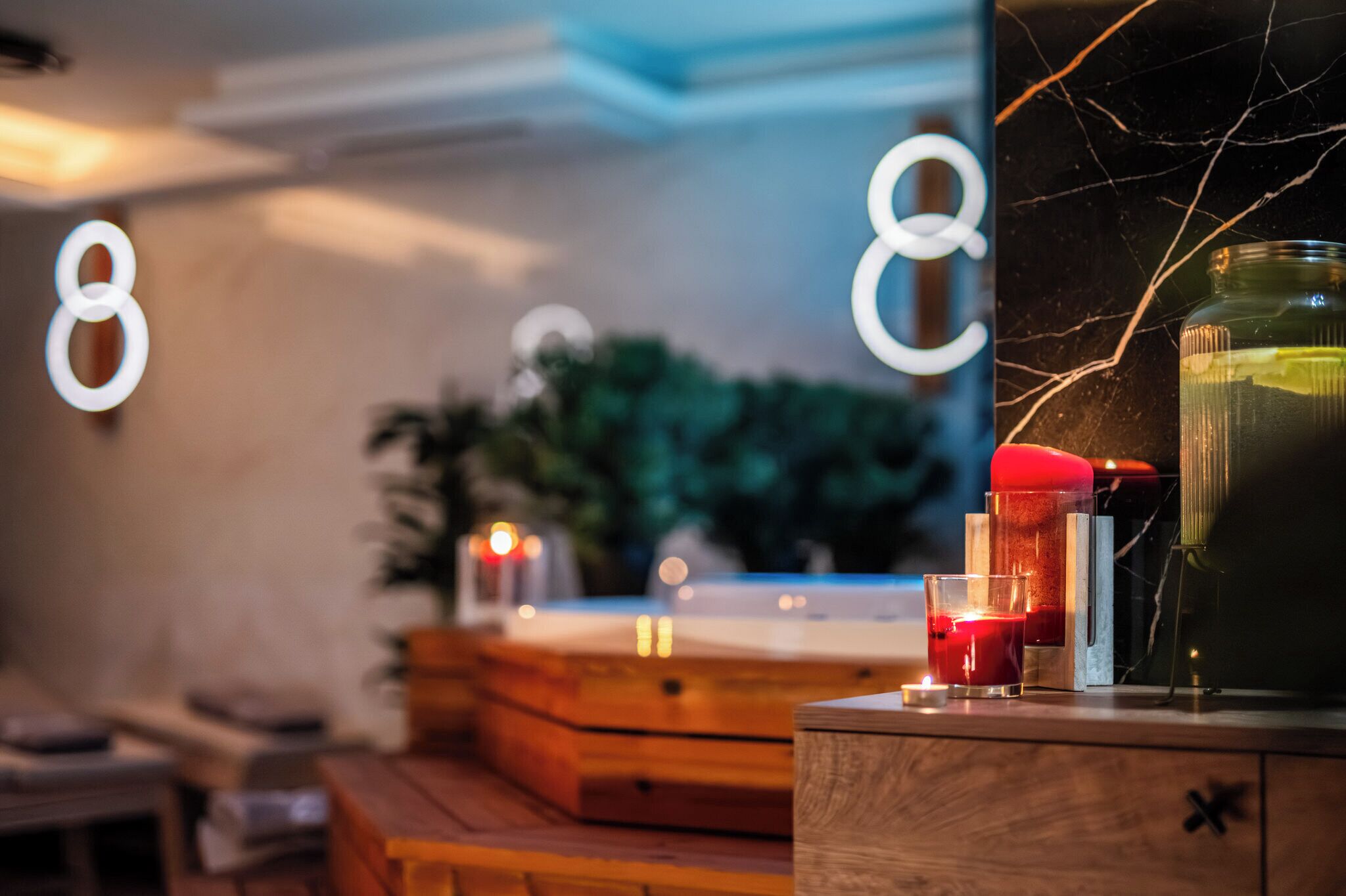 Une pièce chaleureuse avec un meuble en bois, un récipient en verre et des bougies posées sur une table.