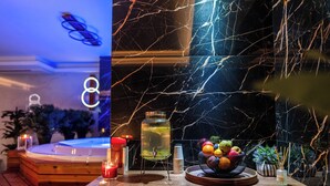 Um banco de madeira com um recipiente de vidro e velas, uma cesta de frutas e uma pequena planta sobre uma mesa de madeira.