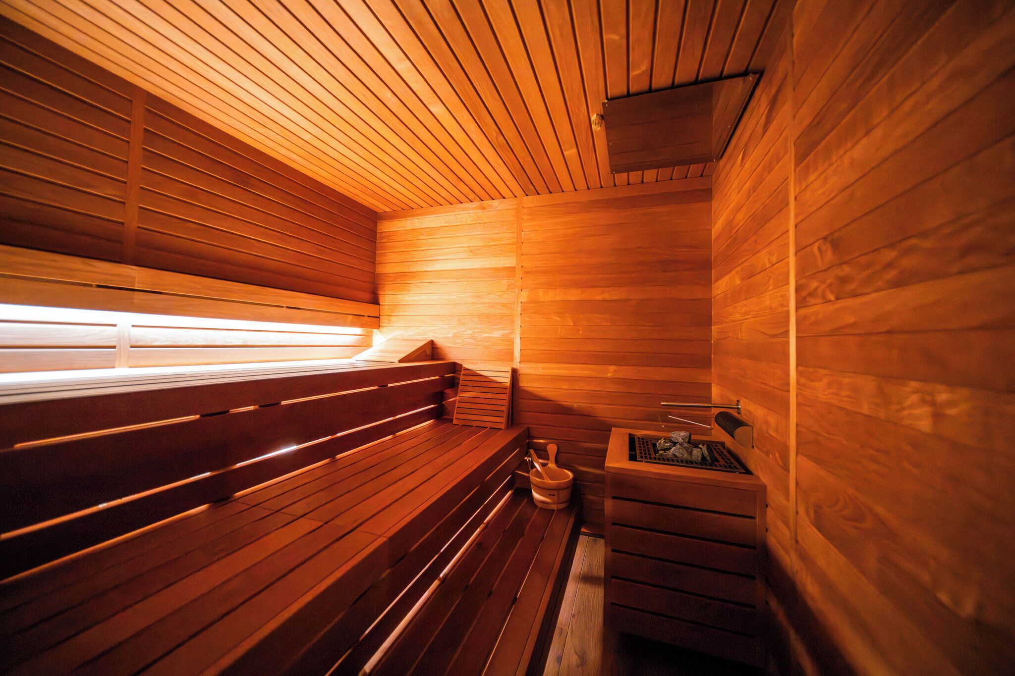 A sauna with wooden benches and a small wooden table with a bucket and brush.