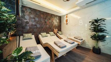 Un cuarto de spa con tres camillas de masaje, un detalle decorativo en la pared y una planta en maceta.