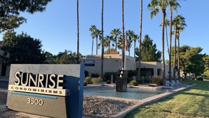 A sign for Sunrise Condominiums with a clear view of the building and palm trees in the background. - Charming villa on golf course in Old Town Scottsdale (Scottsdale)