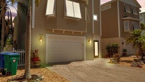 Une maison à deux étages avec un garage, des palmiers et une allée.