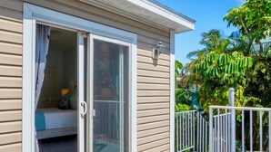 Une propriété située en bord de mer, dotée d’une porte-fenêtre coulissante donnant sur un balcon, d’une terrasse en bois et d’un fauteuil en osier.