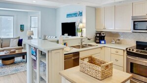 Une cuisine moderne dotée d’un îlot central, d’appareils électroménagers en acier inoxydable et d’un ventilateur de plafond.