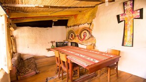 A rustic dining area with a wooden table, chairs, and a patterned tablecloth. - We are Hostal CasArte Takubamba where you can rest an enjoy! (Sucre, Bolivia)