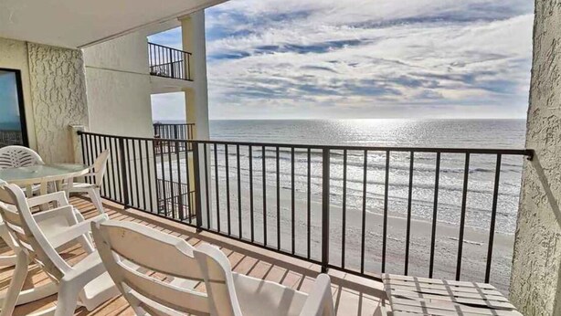 A balcony with a view of the ocean, white plastic chairs, and a table. - Wall-to-wall ocean views! Dog friendly! Oceanfront balcony with stunning views. (North Myrtle Beach)