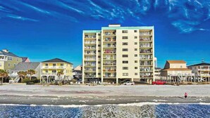 A beachfront hotel with multiple floors, balconies, and a sandy beach in the foreground. - Wall-to-wall ocean views! Dog friendly! Oceanfront balcony with stunning views. (North Myrtle Beach)