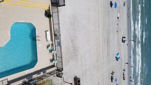An aerial view of a beach with a swimming pool, beach umbrellas, and people. - Wall-to-wall ocean views! Dog friendly! Oceanfront balcony with stunning views. (North Myrtle Beach)