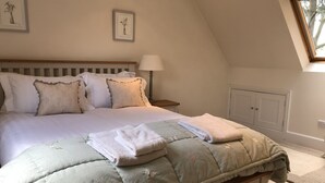 Un lit bien fait, avec une couette verte matelassée, des oreillers et des serviettes pliées.