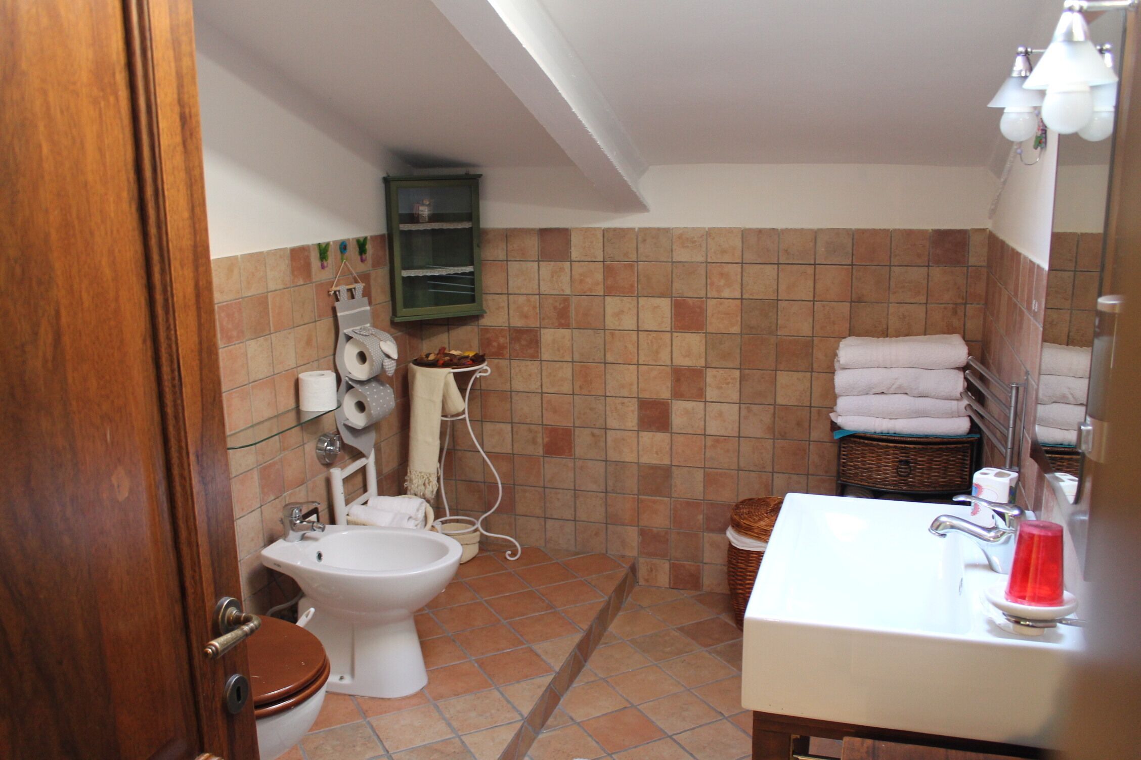 Une salle de bain équipée de toilettes, d’un bidet, d’un lavabo et d’un miroir.