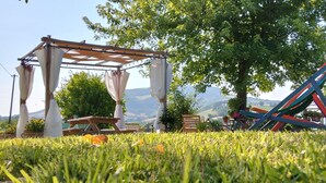 Un jardín con un porche de madera, una mesa de picnic y un tobogán de colores.