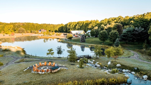 A lakeside property with a cabin, outdoor seating, and a pond. - Cozy 2 Bedroom-2 Bath Cottage Near Ski Resorts! Stay at True North Golf Club (Harbor Springs)