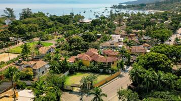 Zona residencial com casas, palmeiras e vista para o mar com barcos.