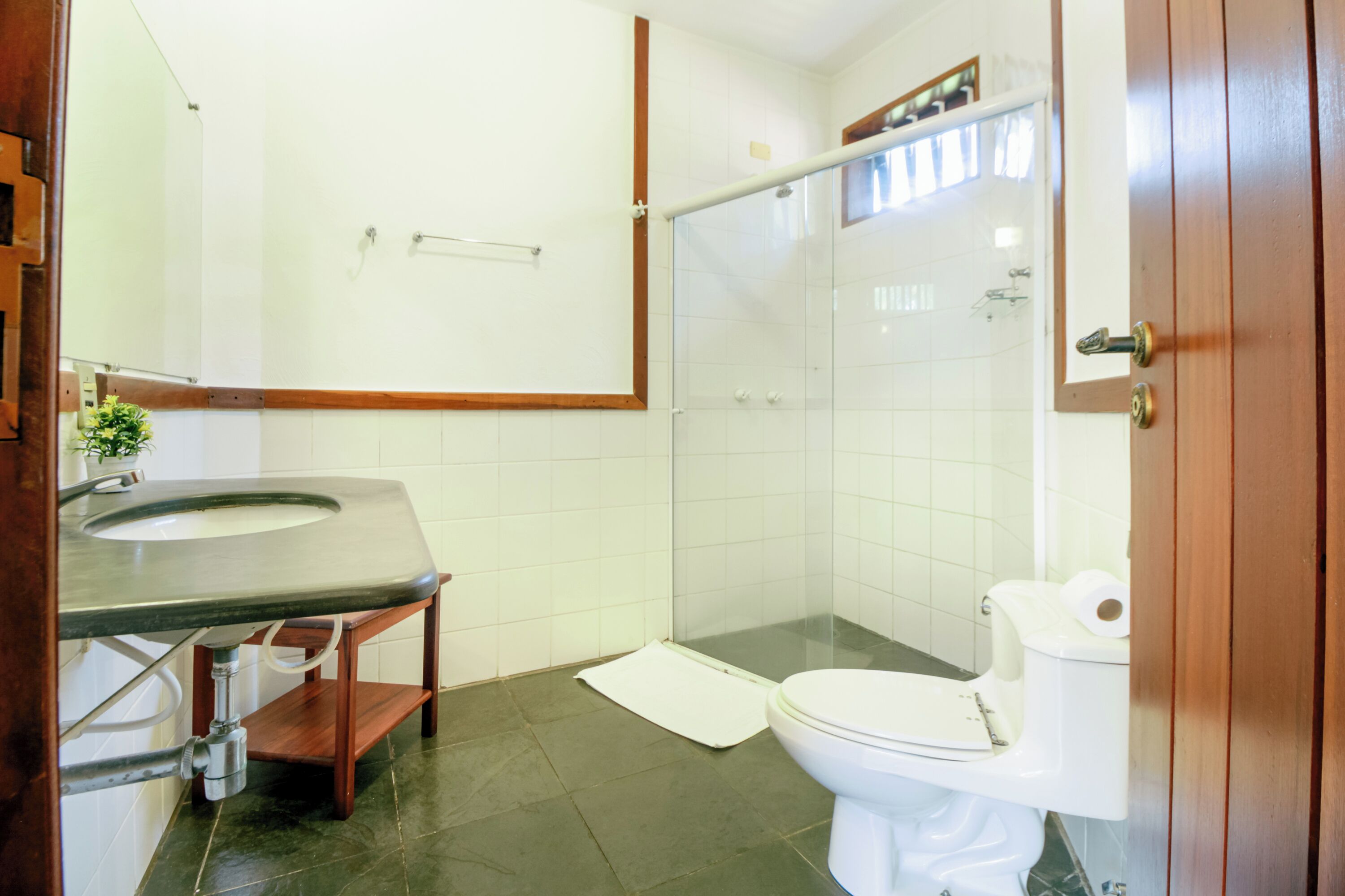 Un baño con inodoro, lavamanos y cabina de ducha de vidrio.