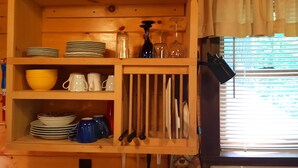 A wooden kitchen shelf with dishes, mugs, and utensils. - Superior Chalet Hemlock (Wilmington)