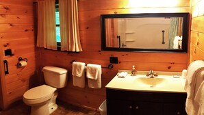 A wooden cabin bathroom with a toilet, sink, and mirror. - Superior Chalet Hemlock (Wilmington)