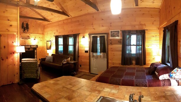 A wooden cabin interior with a dining area, a sofa, a chair, and a bed. - Superior Chalet Hemlock (Wilmington)