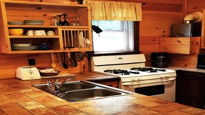 A kitchen with a gas stove, sink, and wooden cabinets. - Superior Chalet Hemlock (Wilmington)