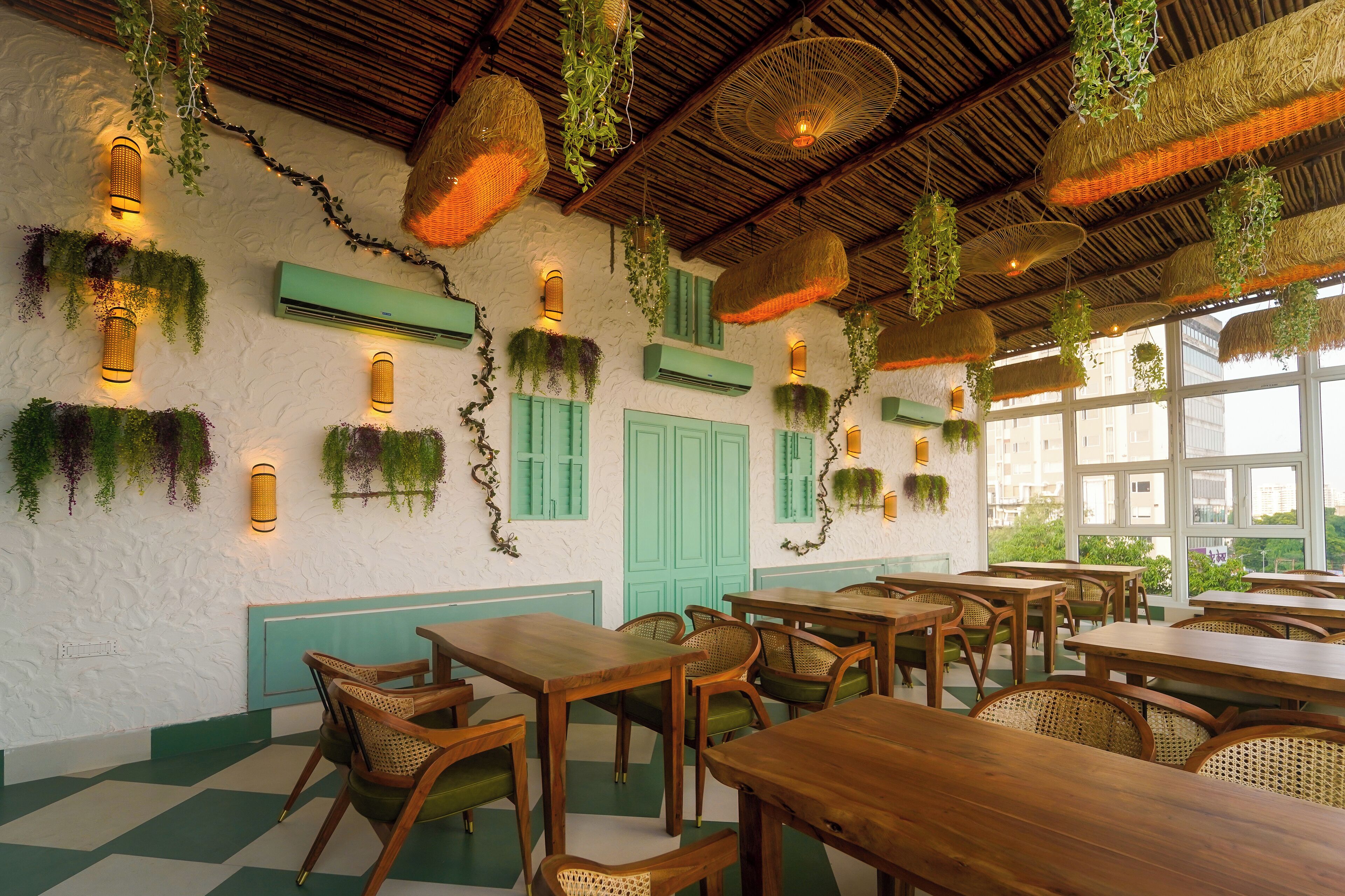 A restaurant with wooden tables and chairs, hanging plants, and green shutters.