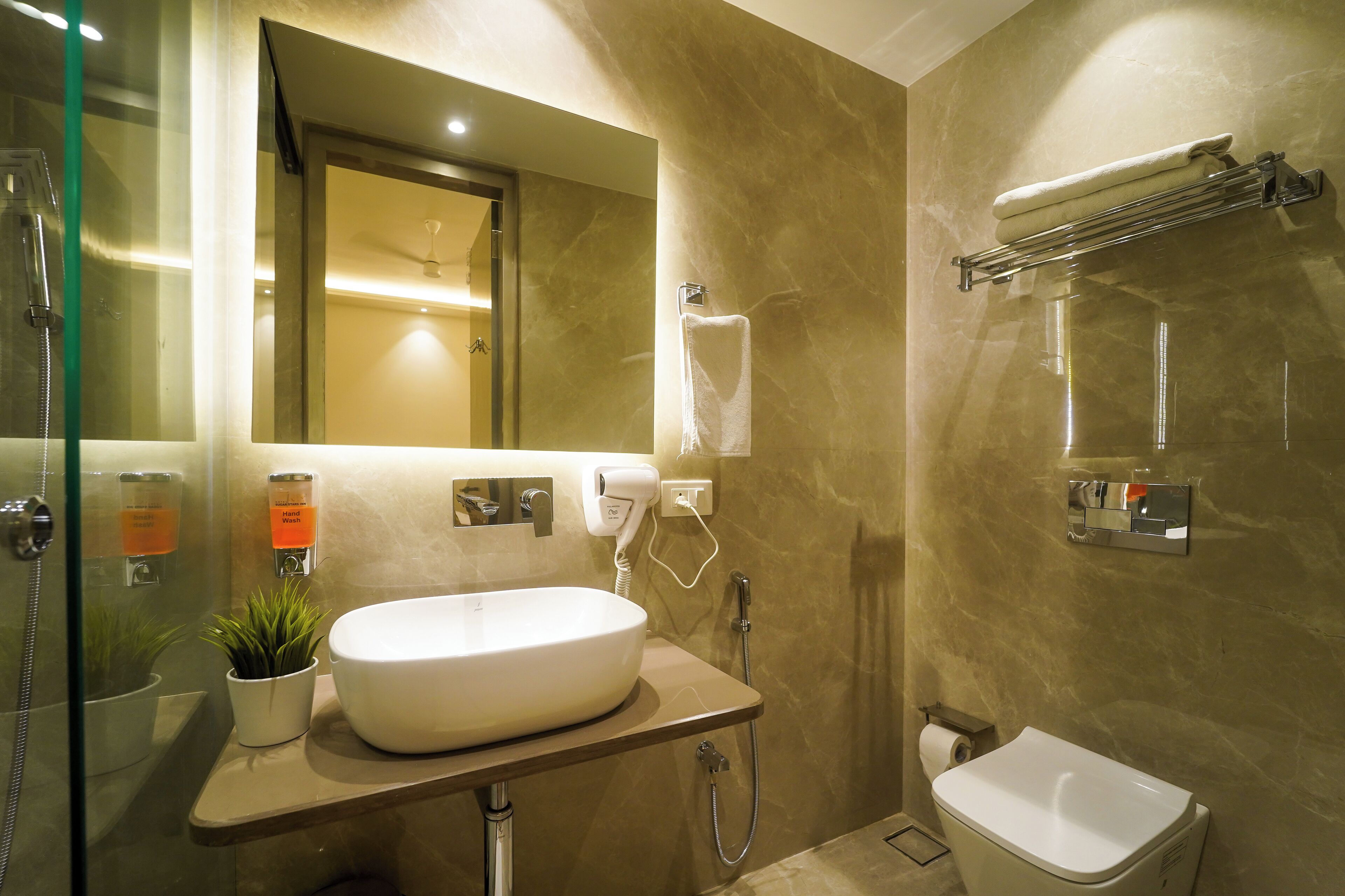 Un baño moderno con un lavamanos grande, un cabezal de ducha de mano, un perchero para toallas y un inodoro.