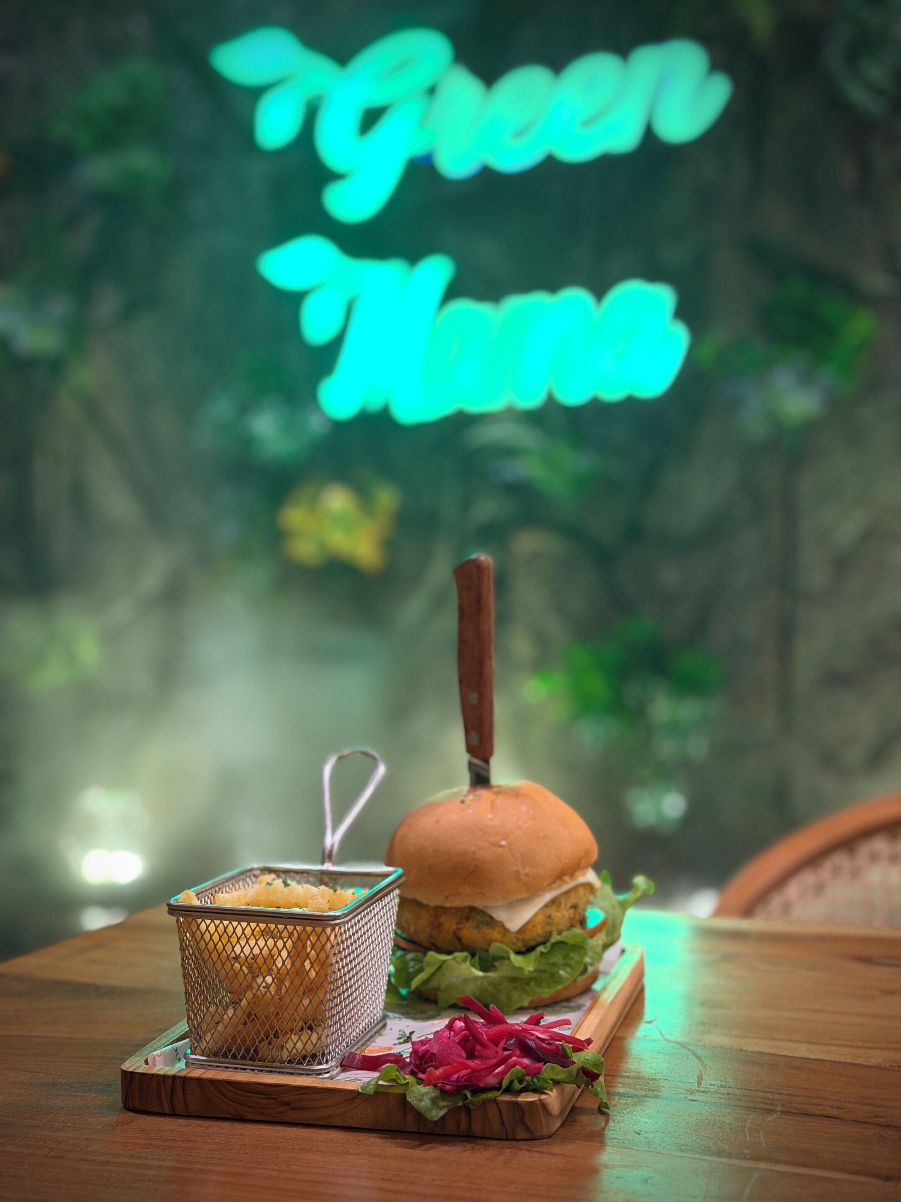 A burger with a bun, lettuce, and a side of fries on a wooden board.