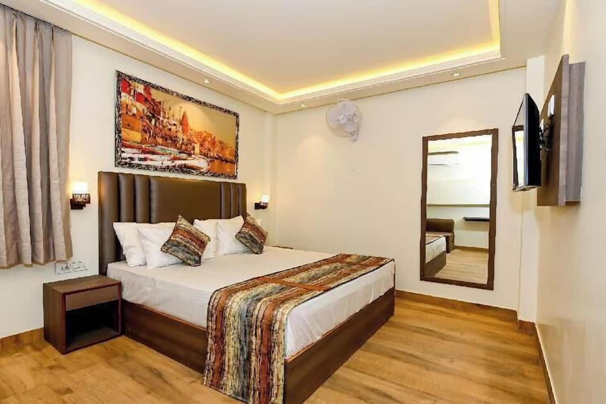 A bedroom with a bed, a nightstand, a painting, a mirror, and a television.