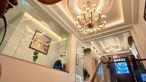 A grand staircase with a glass railing, a chandelier, and a framed picture on the wall. - Sugar Stars Inn (Varanasi)